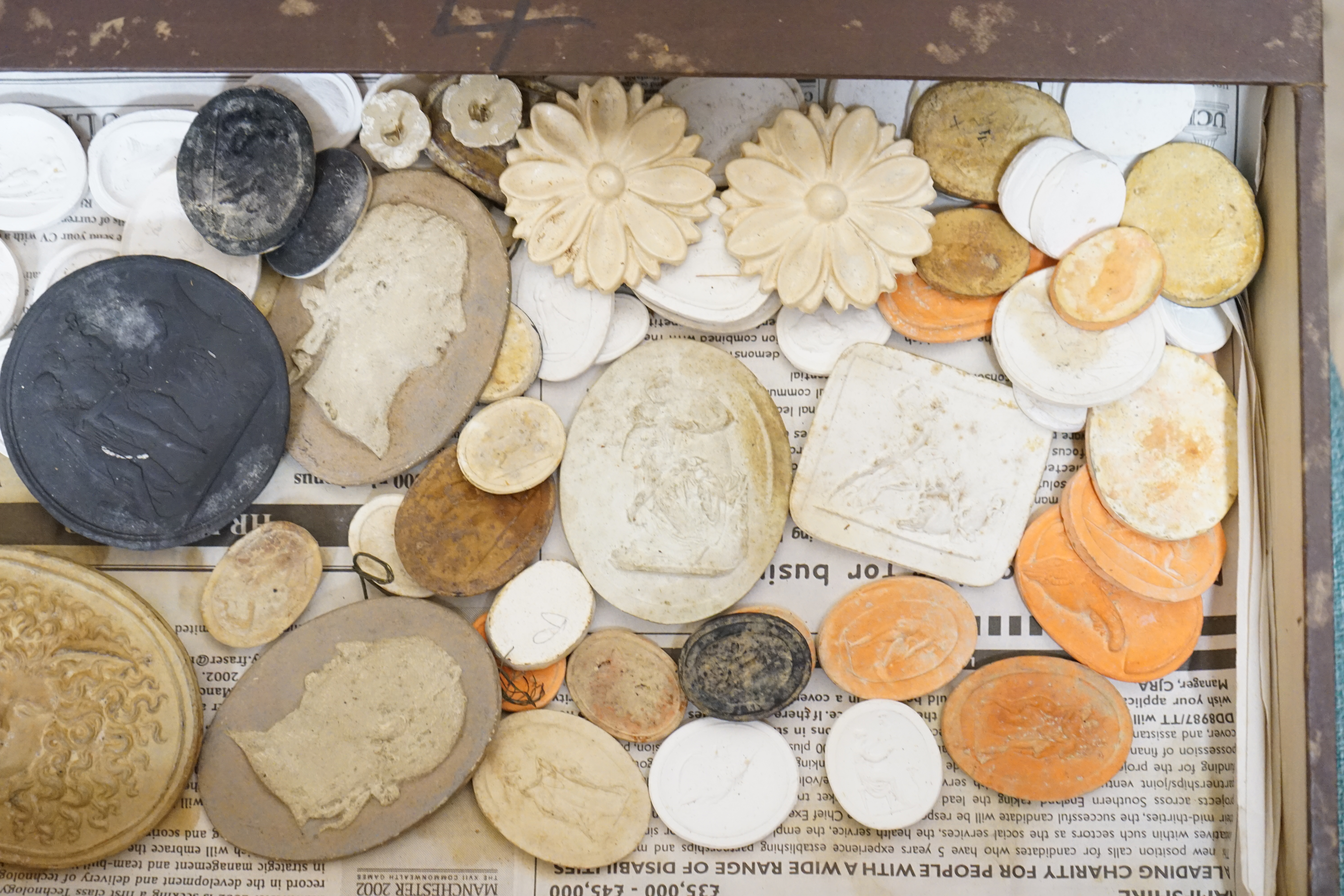 A case containing a collection of various plaster cameos and moulds. Condition - varies